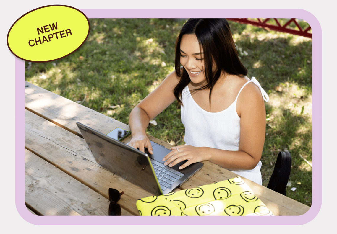 A woman with her laptop on a park table with a sticker that reads 