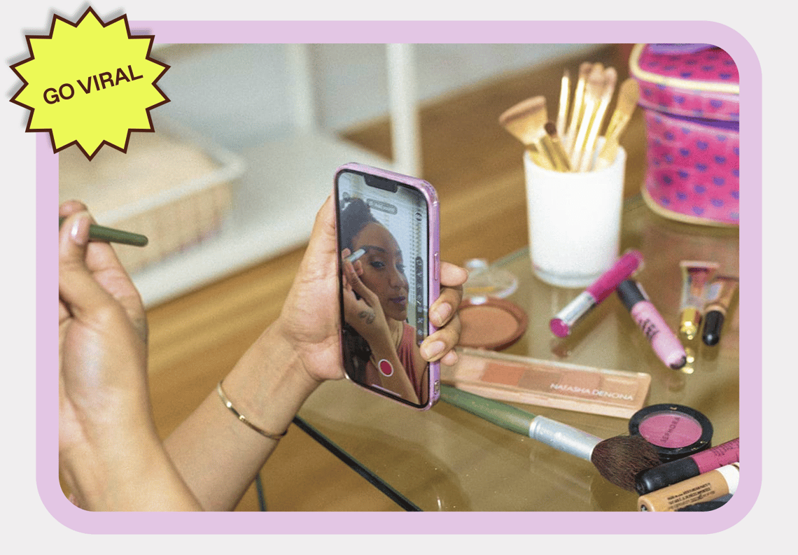 A content creator woman filming her make-up tutorial with a sticker that reads 